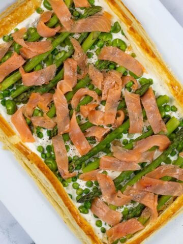 Smoked salmon and spring vegetable tart on a white rectangular serving platter.
