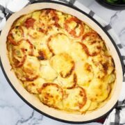 Creamy gratin of smoked haddock, tomatoes and potatoes in a deep oval casserole dish.