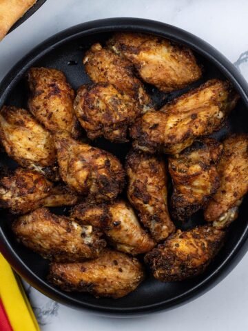 Easy air fryer Spanish chicken wings in a black serving bowl.