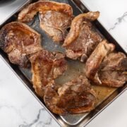 6 perfect pan-fried lamb chops resting on a tray.