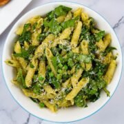 Pesto, peas and spinach pasta salad in a light blue trimmed serving bowl.