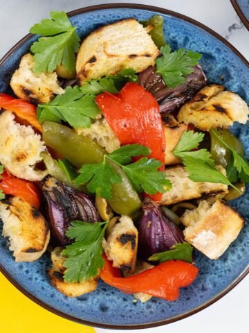 Barbecued mixed pepper salad for 2 in a blue patterned bowl with a yellow napkin on the side.
